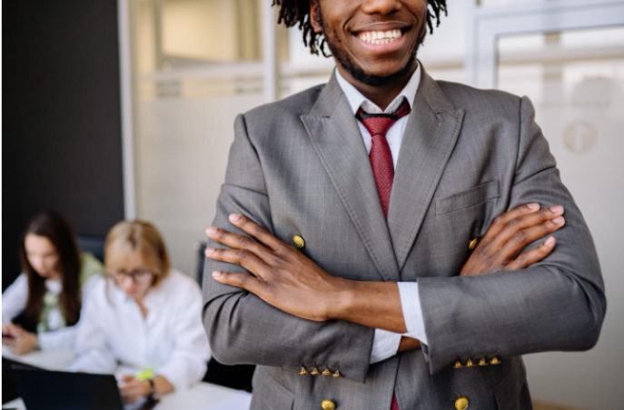 A young man smiling in the front of a group of people in an office.